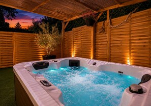 A hot tub with a wooden deck and a wooden fence in the background. - Le Repos du Poète (Nestier)