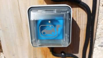 Une borne de recharge pour voitures, dotée d’une icône bleue et reliée à un câble noir.