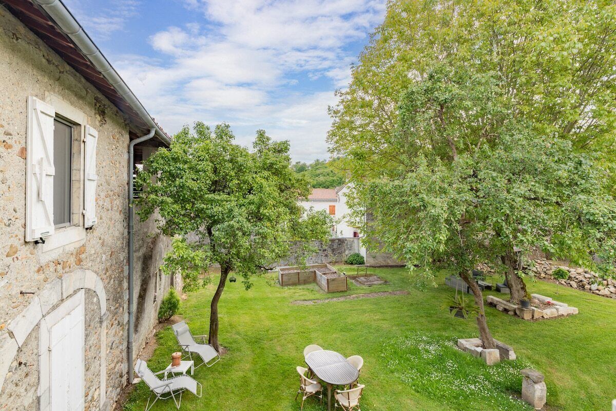 A rustic stone building with a garden patio featuring outdoor furniture.
