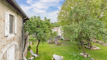 A rustic stone building with a garden patio featuring outdoor furniture.