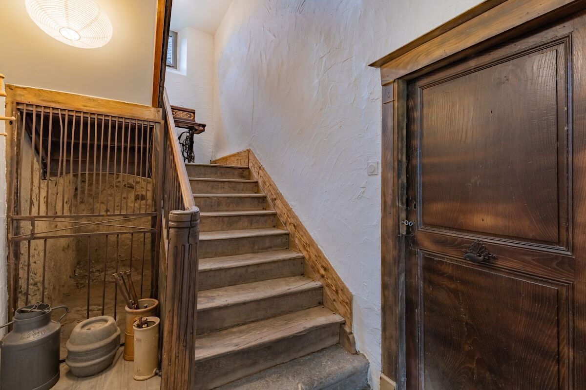 A wooden staircase with a metal railing, a wooden door, and a light fixture.