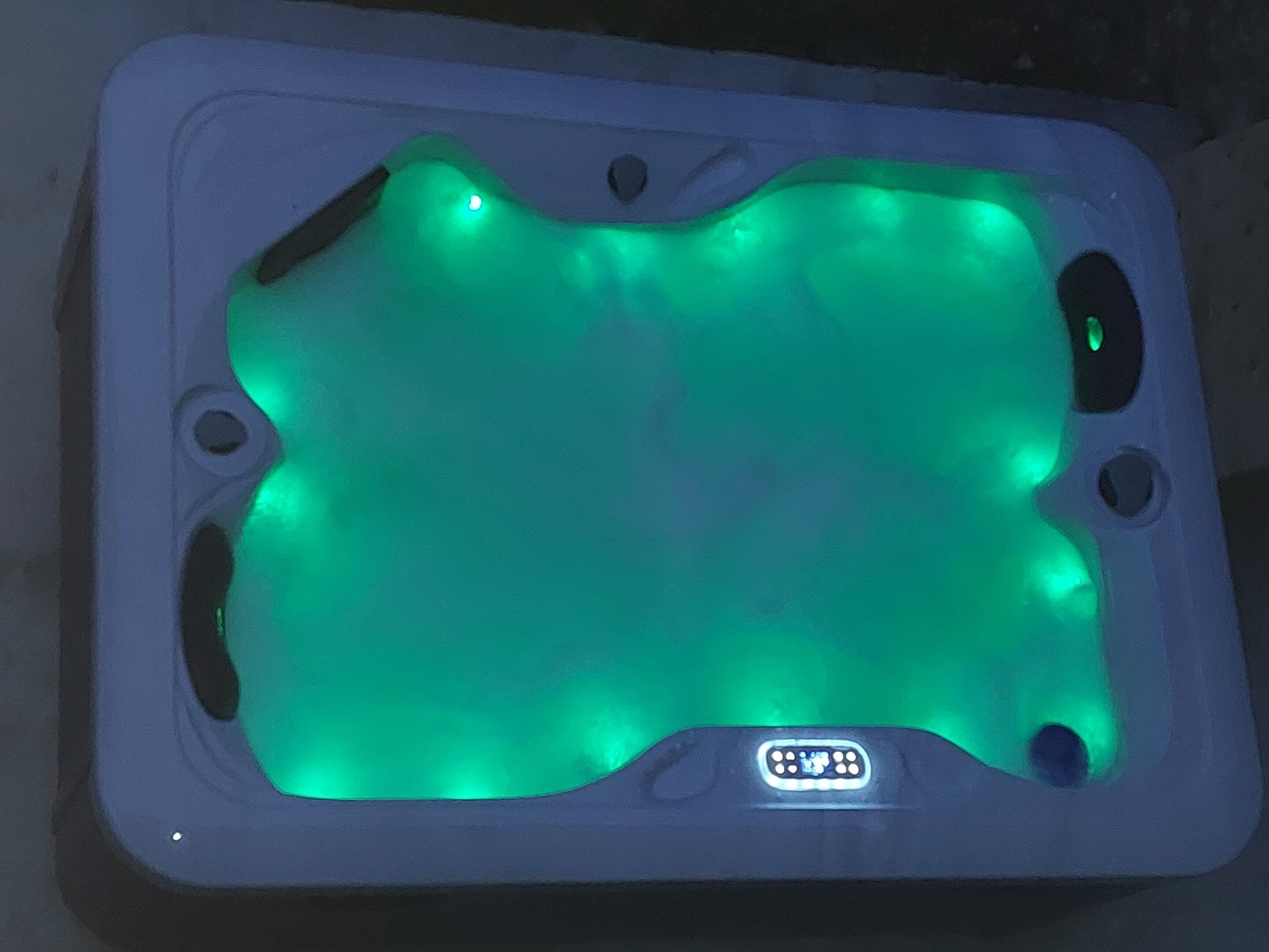 A rectangular hot tub with a green light.