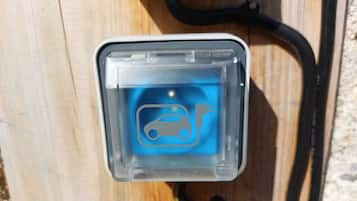 Une vue claire d’une borne de recharge pour véhicules électriques, avec une prise et un câble.