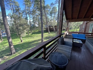 Une terrasse en bois, agréée de mobilier d’extérieur, donnant sur un espace verdoyant planté d’arbres.