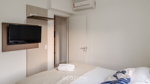 A hotel room with a bed, a TV mounted on the wall, an air conditioning unit, and a door leading to another room. - PVI - Charming Apartments Just 450m From the Seafront in Ubatuba/sp (Ubatuba)