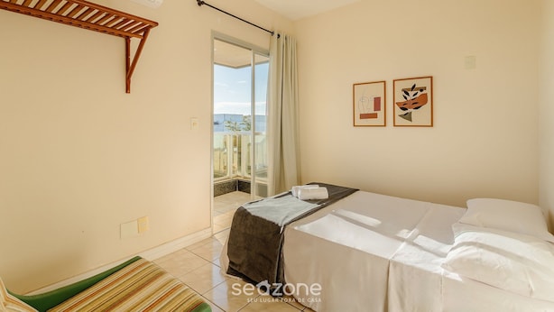 Ein Schlafzimmer mit einem Bett, einem Holzbodenregal, einem Deckenventilator und Blick ins Freie.