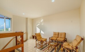 Un vaste espace de vie agrémenté d’un escalier en bois, d’une grande fenêtre offrant une belle vue et d’un ensemble de quatre fauteuils confortables.