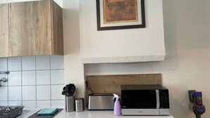 A kitchen with a wooden cabinet, a framed picture on the wall, a microwave, a toaster, and a spray bottle. - Your apartment with free prking in St Etienne (Saint-Étienne)