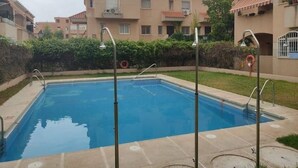 A rectangular swimming pool with a clear blue surface, surrounded by a concrete deck.