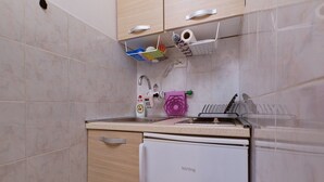 Una cocina compacta con refrigerador, pileta y encimera.