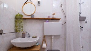Un baño con lavamanos, inodoro, ducha y espejo.