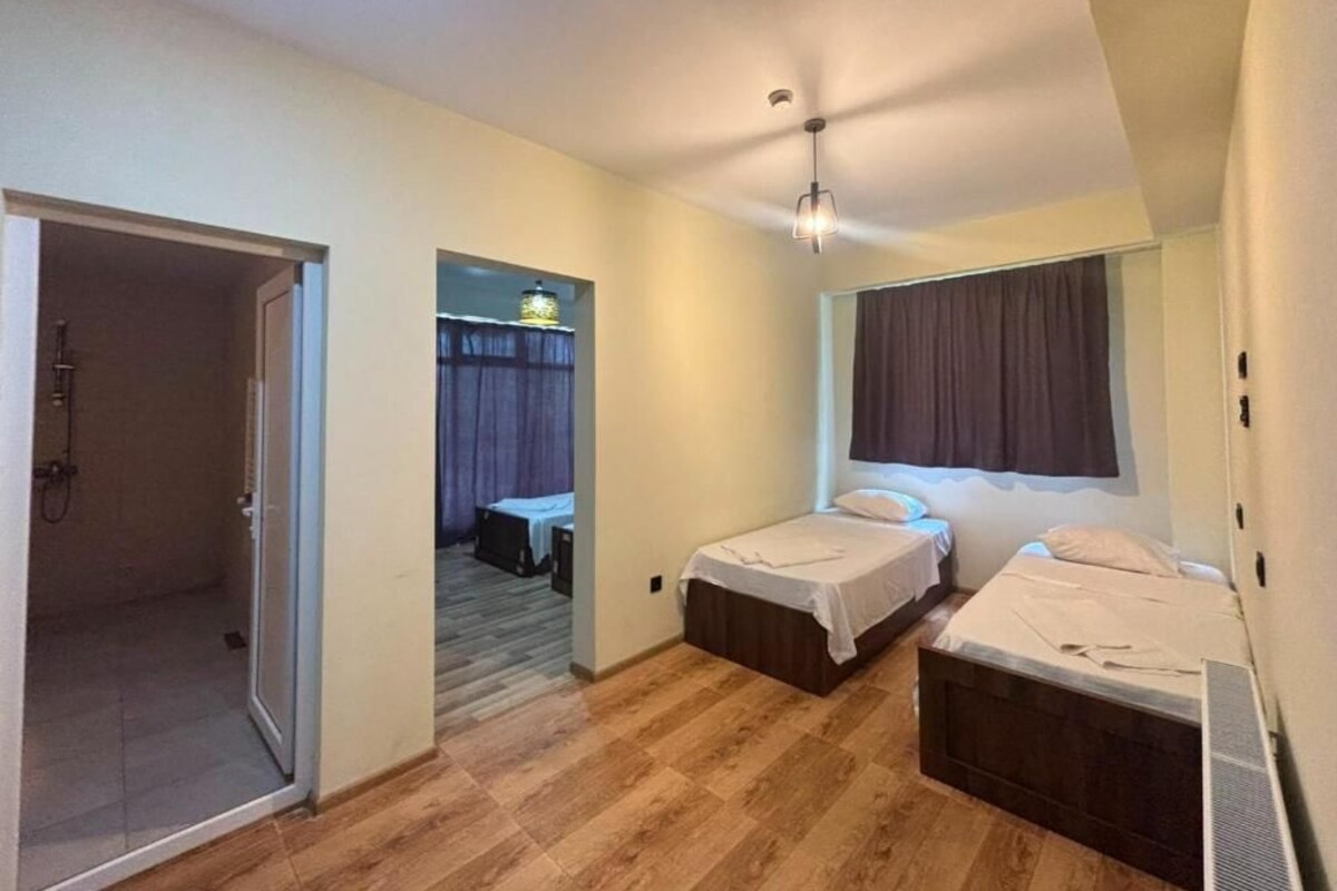 Una habitación con dos camas, una zona de ducha y un pasillo que conduce a otra habitación.