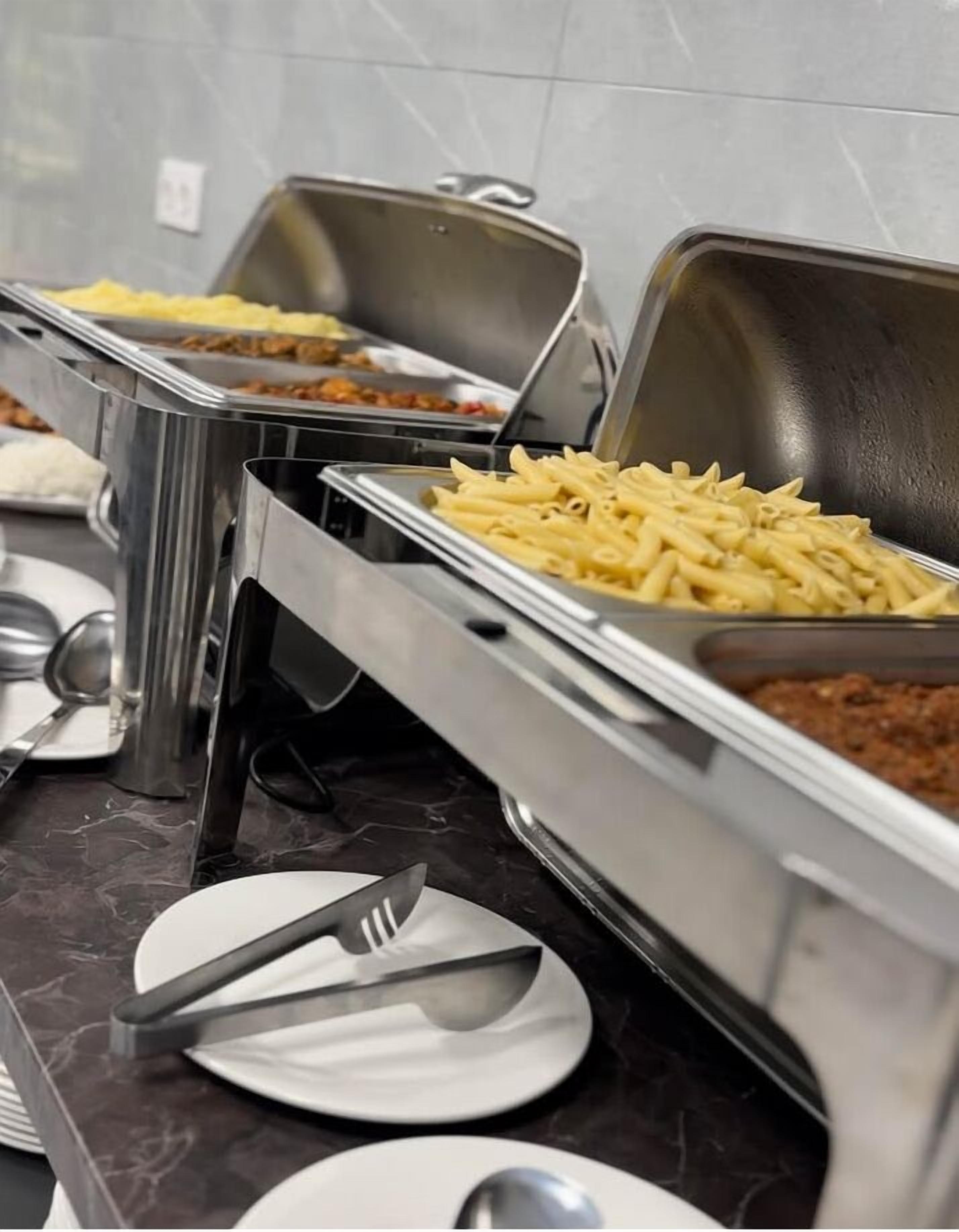 A buffet setup with various dishes in metal serving trays.