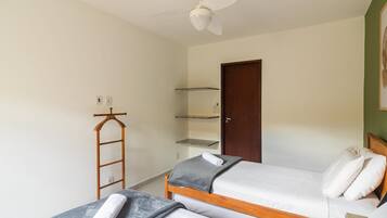 A bedroom with two single beds, a wooden ladder, a ceiling fan, and a door.