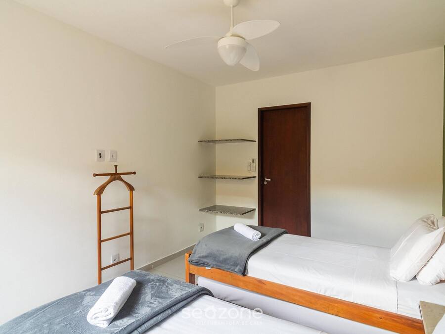 A bedroom with two single beds, a wooden ladder, a ceiling fan, and a door.