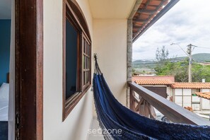 A hammock on a balcony with a view of a town and hills. - Beautiful House in Cabo Frio Ptb0105 (Cabo Frio)
