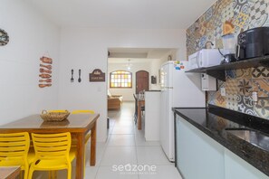 A kitchen with a dining area, a refrigerator, a microwave, and a coffee maker on the counter. - Beautiful House in Cabo Frio Ptb0105 (Cabo Frio)