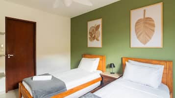 Een slaapkamer met twee bedden, een houten hoofdbord, een nachtkastje met lamp en lijstwerken aan de muur.