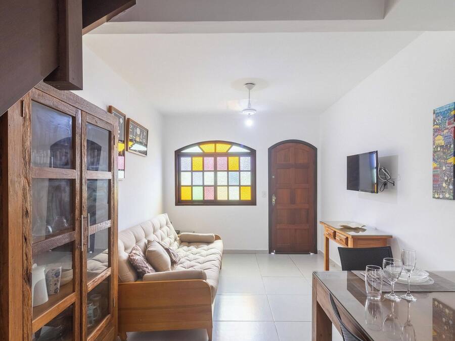 A living room with a sofa, a cabinet, a television, and a dining area with a table and chairs.