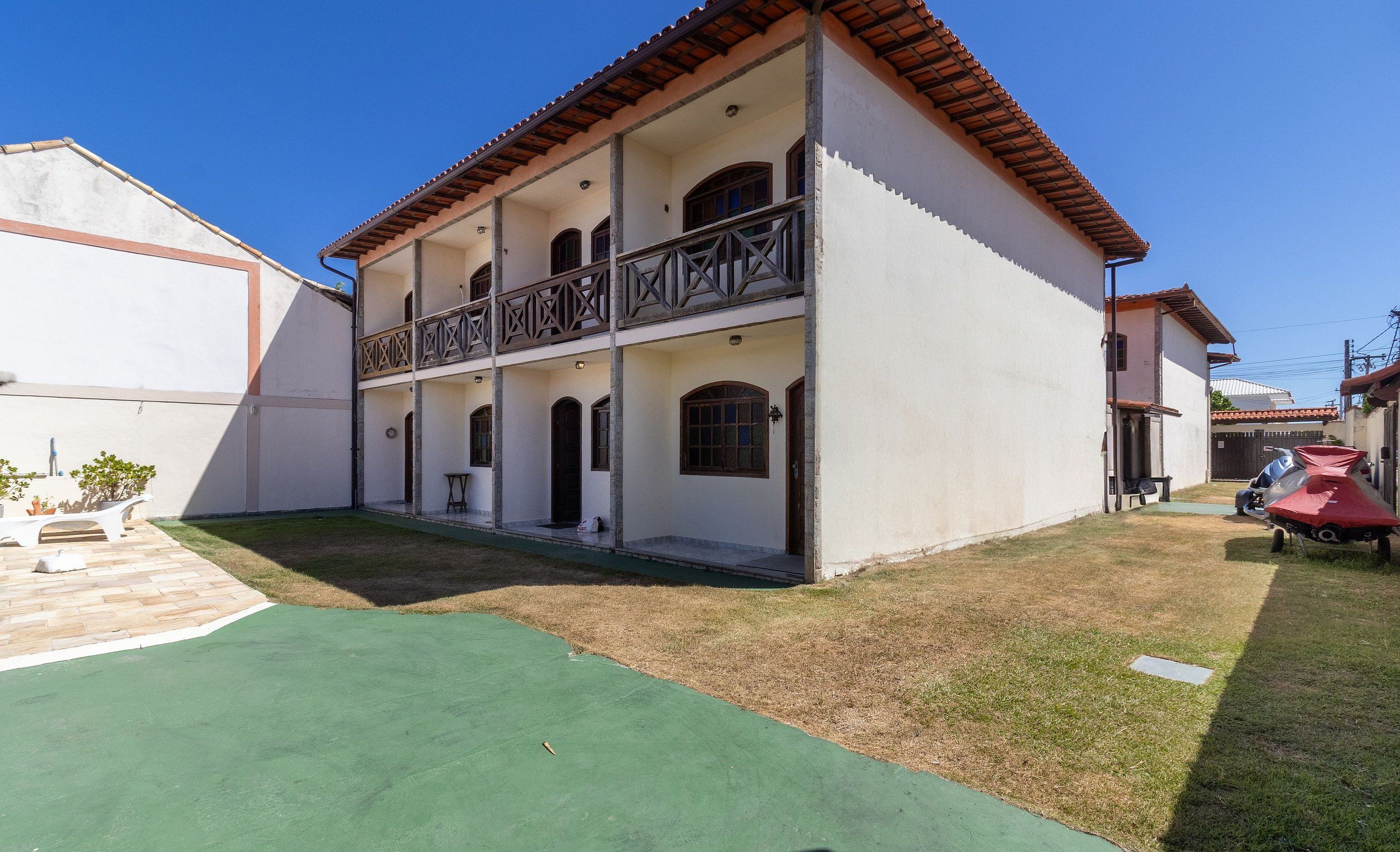 A two-story building with a balcony, a small lawn, and a parked scooter.