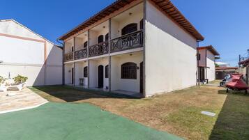 A two-story building with a balcony, a small lawn, and a parked scooter.