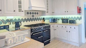 Una cocina con armarios blancos, estufa a gas, horno, microondas y tostadora.