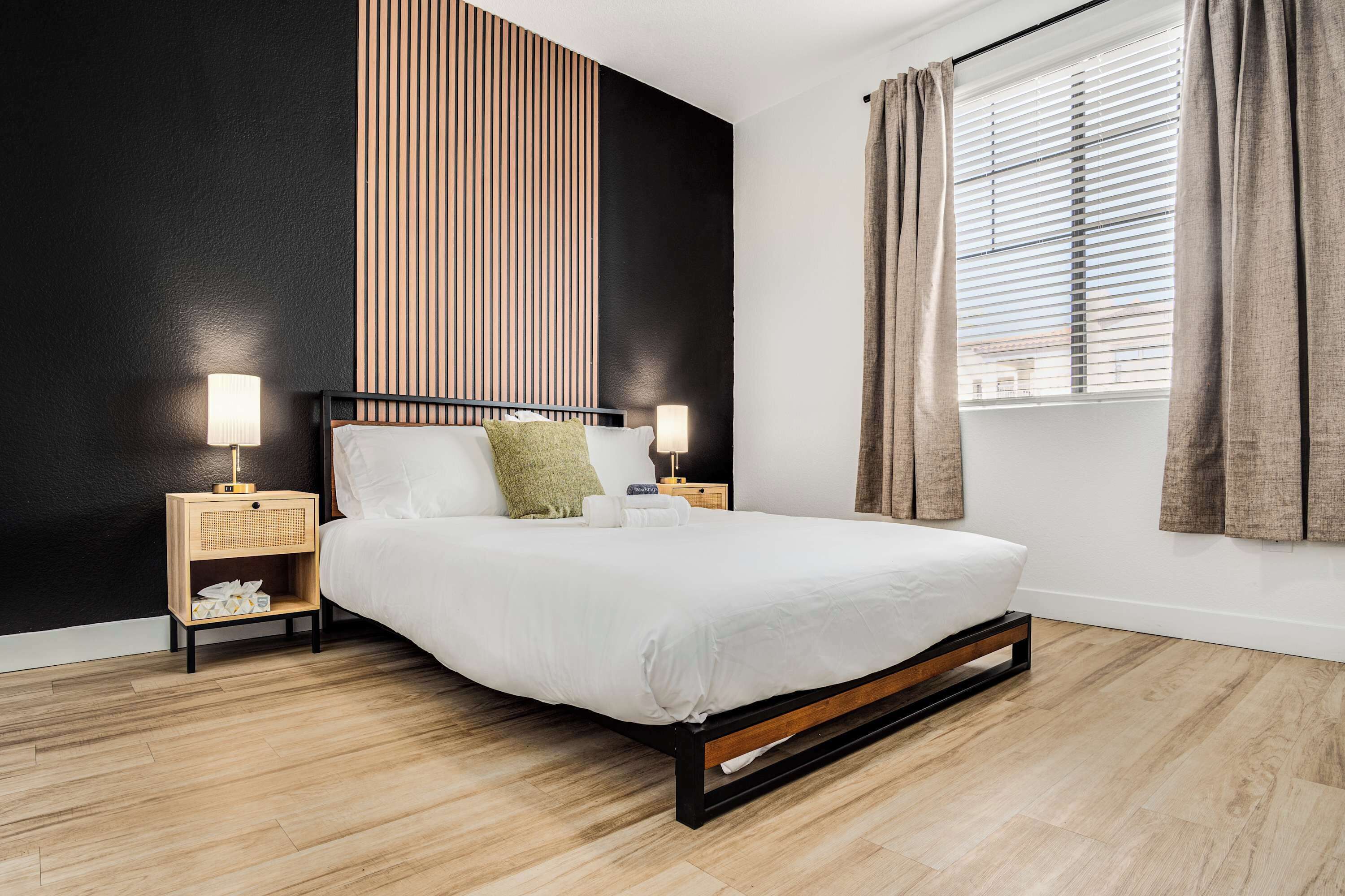 A modern bedroom with a bed, bedside tables, and a window with curtains.