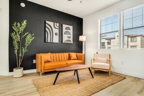 Una sala de estar moderna con una pared de acento negra, un sofá, un sillón, una mesa de centro y una planta en maceta.