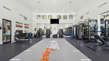 Une salle de sport dotée d’un grand miroir central, d’équipements de musculation et de décorations murales inspirantes.