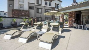 A rooftop lounge area with sun loungers, a table, and an umbrella.