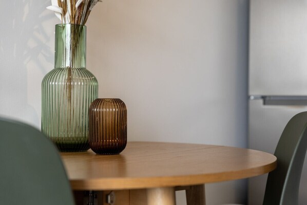 A round wooden table with two vases, one green and one brown, placed on it.