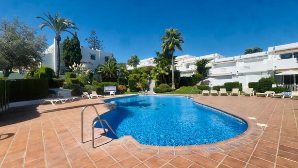 A swimming pool with a tiled deck, surrounded by palm trees and lounge chairs. - Golf Course House with 3 Terraces, heated pool, tennis acess, near beach (Marbella)