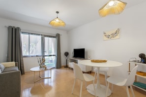 Una sala de estar moderna con un sofá, una mesa de comedor con sillas, un televisor y un elemento decorativo en la pared.