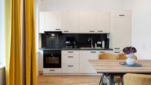 A modern kitchen with white cabinets, a black stove, and a dining area with a wooden table and chairs.
