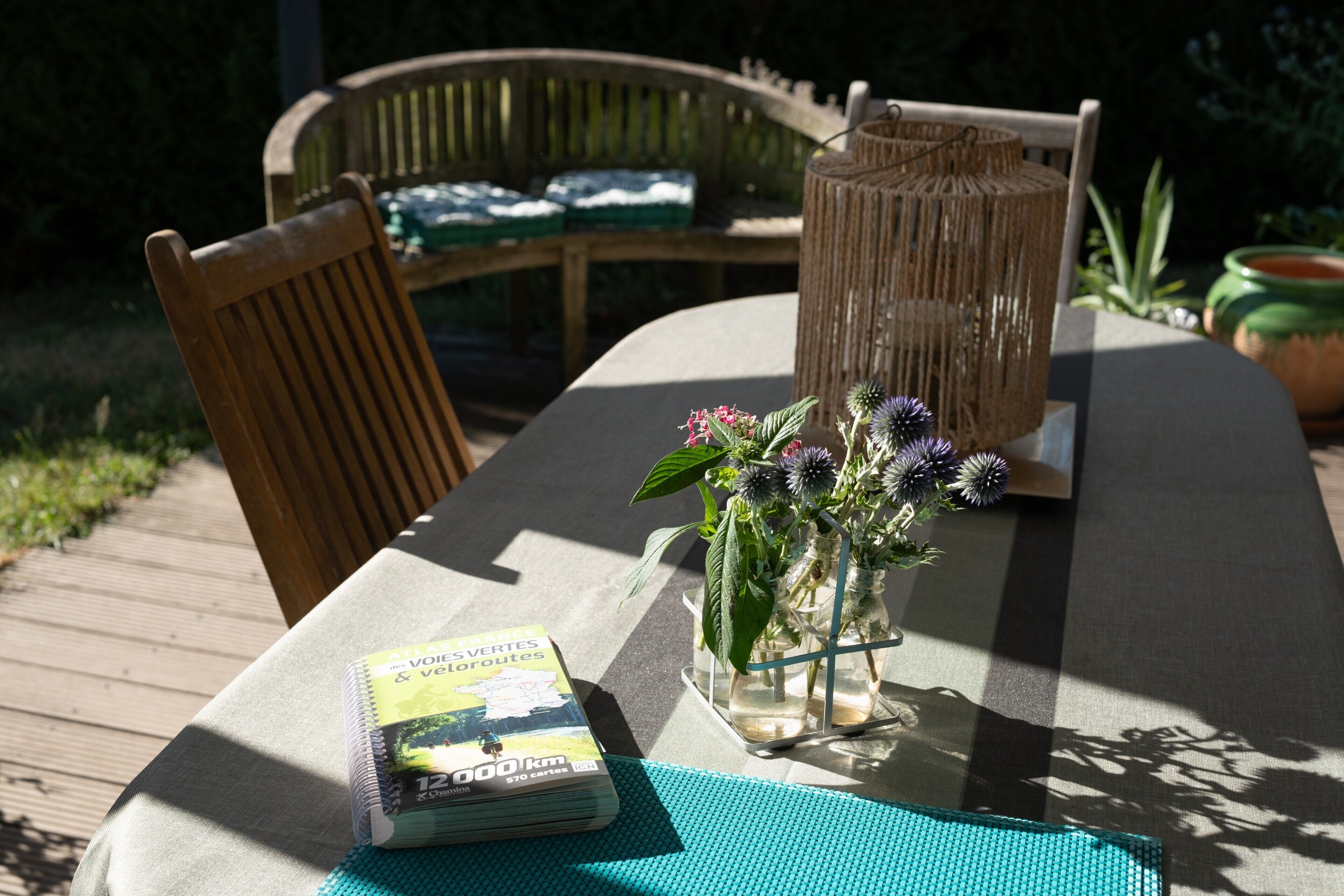 Een tafel met een boek, een vaas met bloemen en een rieten lantaarn.
