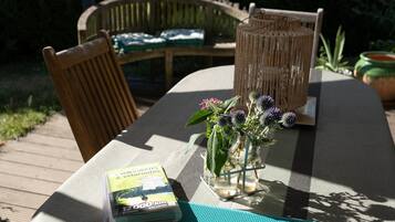 Een tafel met een boek, een vaas met bloemen en een rieten lantaarn.
