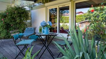 Une terrasse extérieure avec une table et des chaises, entourée de verdure et offrant une vue sur un quartier résidentiel.