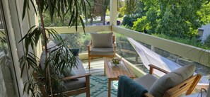 A balcony with a sofa, chair, table, and potted plants. - Room with Private Bathroom and Balcony by the Canal (Charmes)
