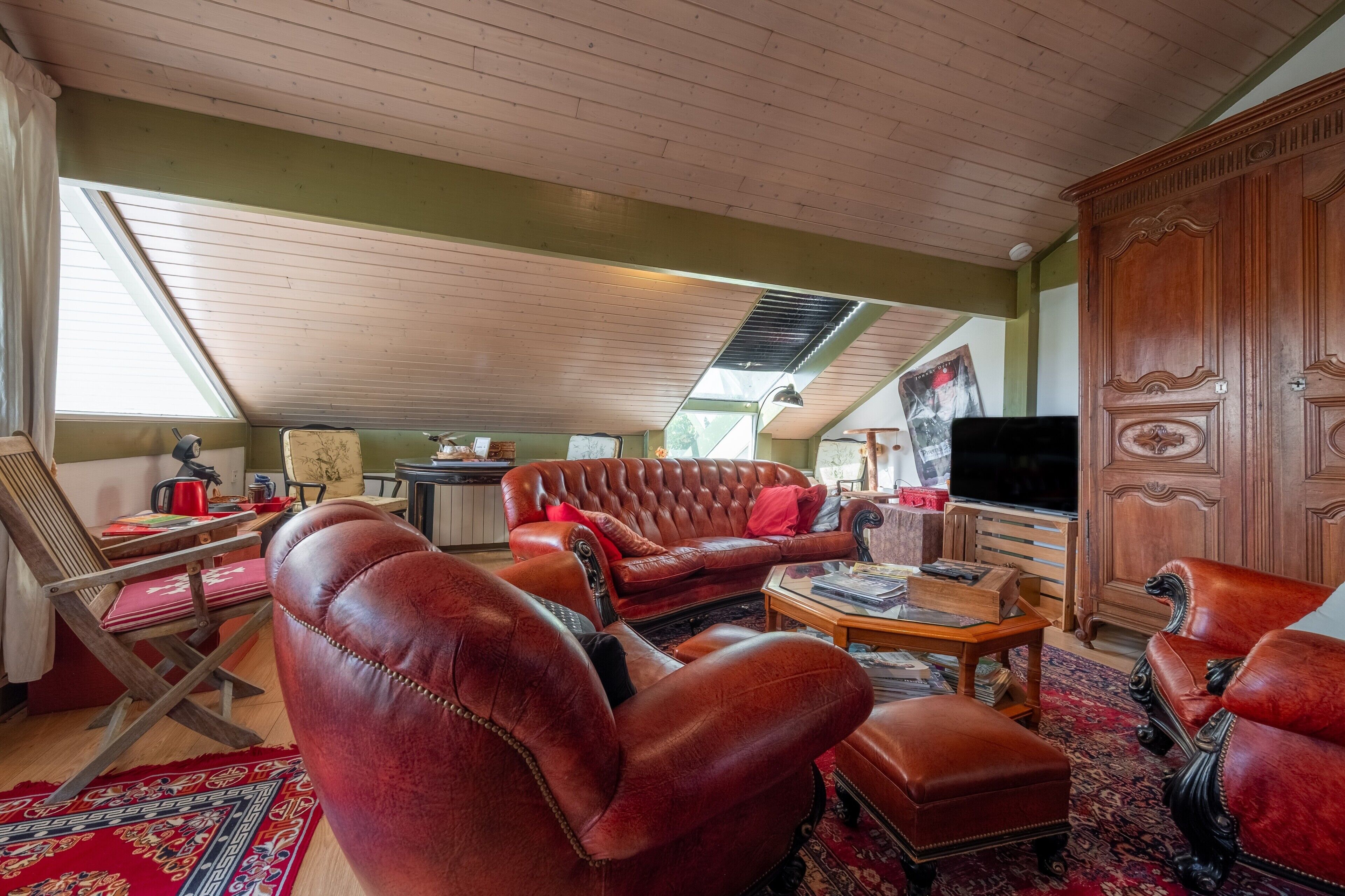 Una sala de estar acogedora con mobiliario de cuero, un televisor y un mueble de madera.