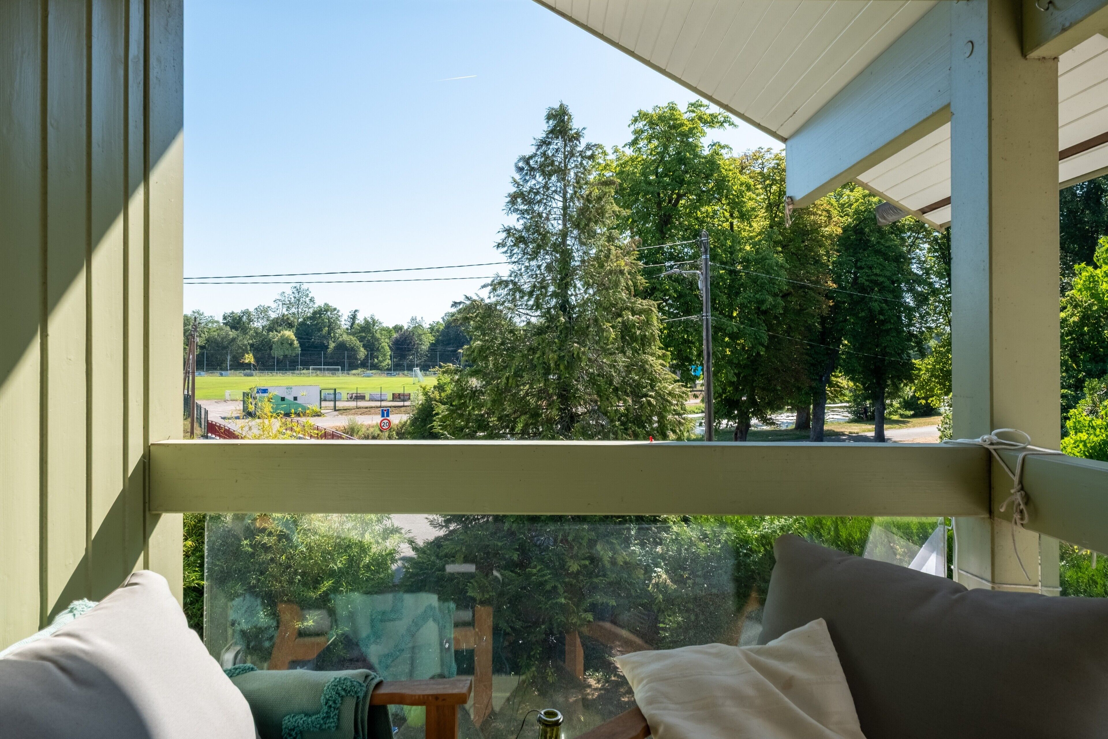 Une pièce avec vue sur un parc, une fenêtre et un fauteuil.