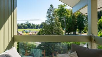 Une pièce avec vue sur un parc, une fenêtre et un fauteuil.