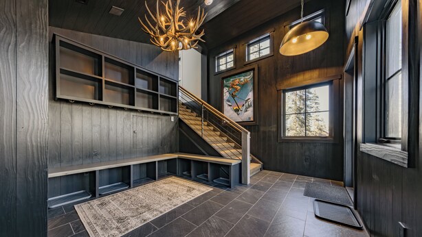 Un interior moderno con una escalera de madera, estanterías empotradas y un ventanal grande.