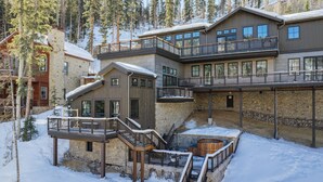 Un edificio de varios pisos con fachada de piedra, balcones de madera y suelo cubierto de nieve.