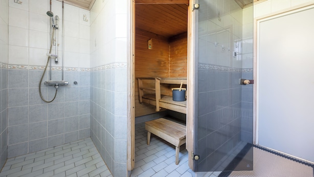 A modern bathroom with a shower, a wooden sauna, and a glass-enclosed shower area.