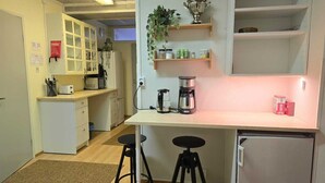 A compact kitchen with a central island, a coffee machine, and a refrigerator.