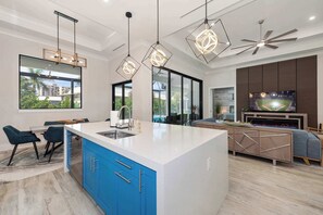 Una cocina moderna con una isla central, armarios azules e iluminación colgante.