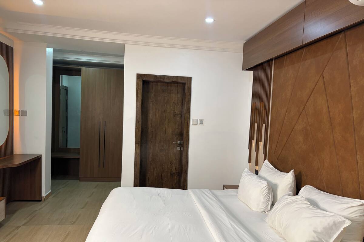 Un dormitorio con una cama grande, cabecera de madera y un armario.