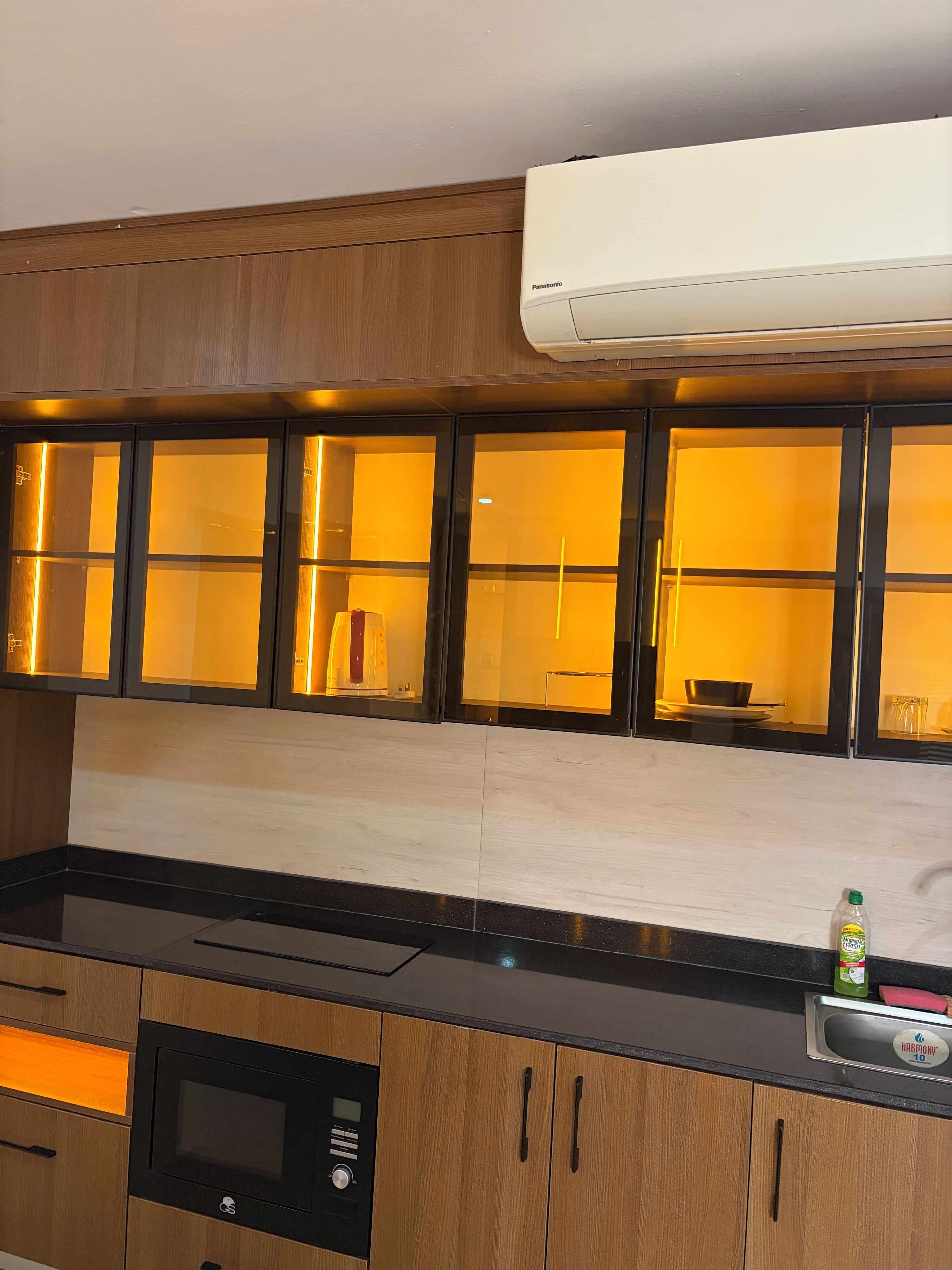 A kitchen with wooden cabinets, a microwave, and an air conditioner.