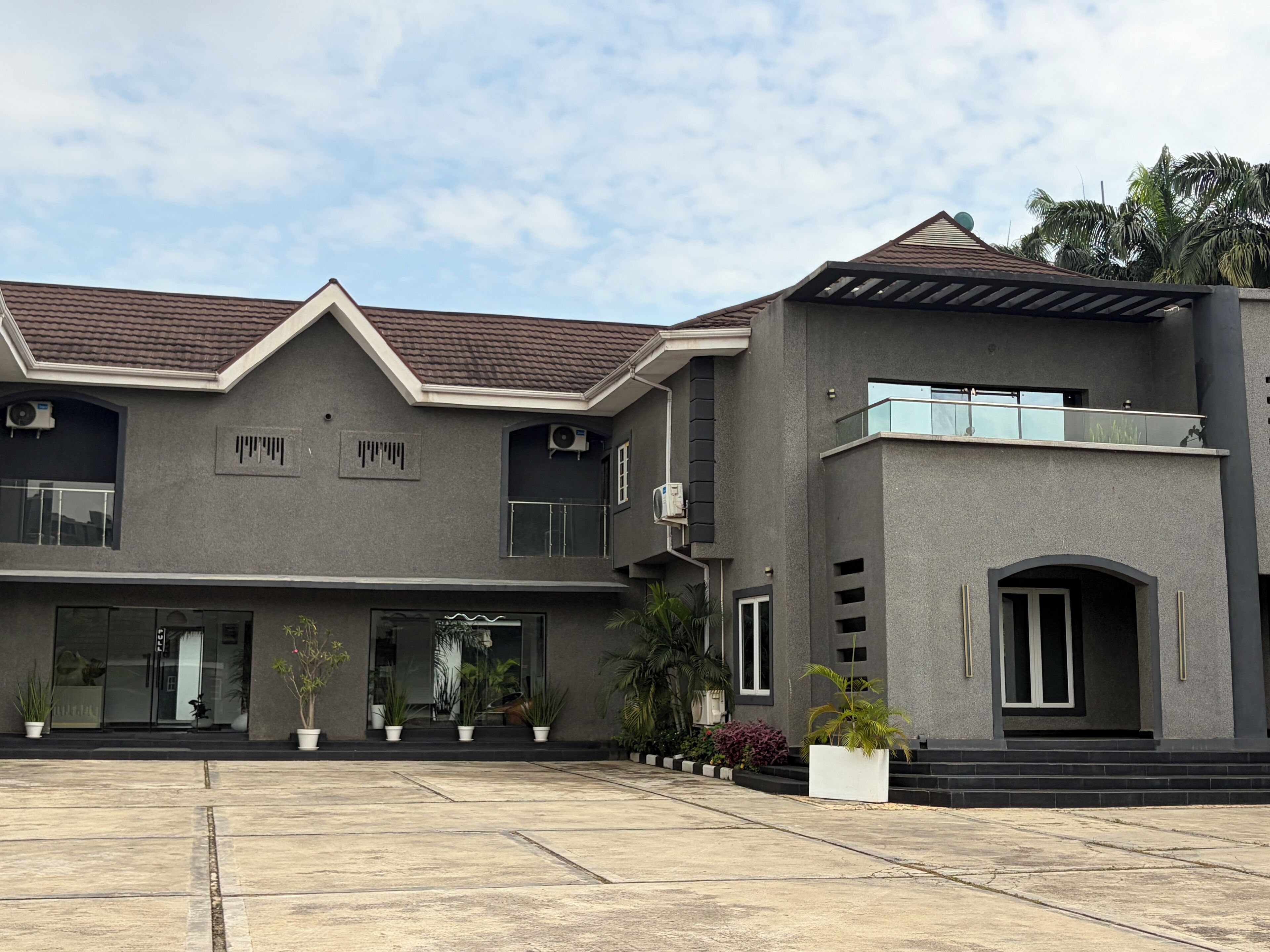 A modern two-story building with a flat roof, large windows, and a balcony.