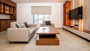 A modern living room with a sofa, coffee table, and TV wall unit. - COLOGNE RESIDENCE  (Abuja)